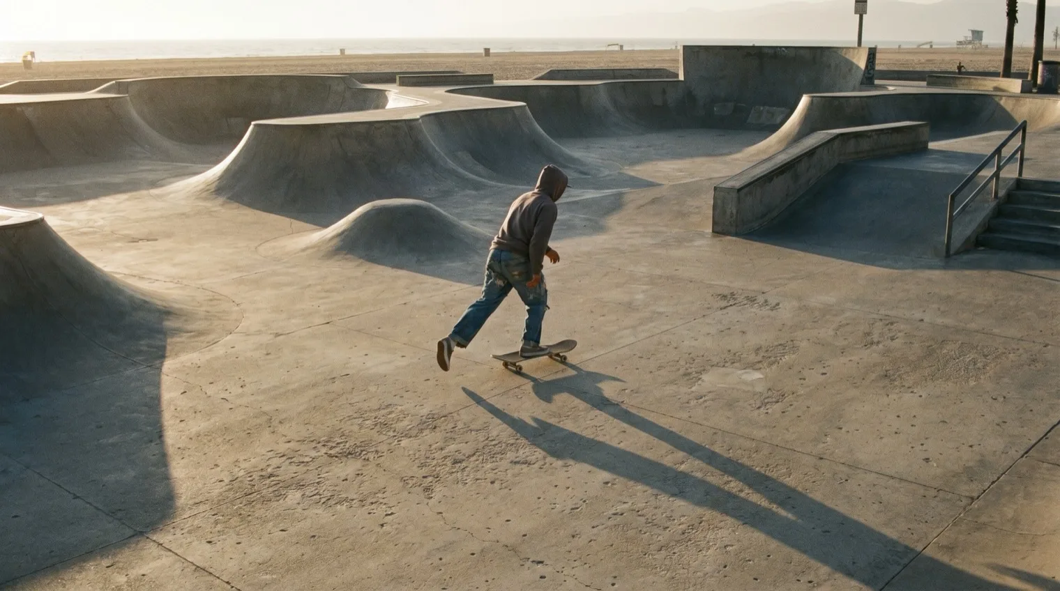 Beginner skater pushing across an empty skatepark in early morning light
